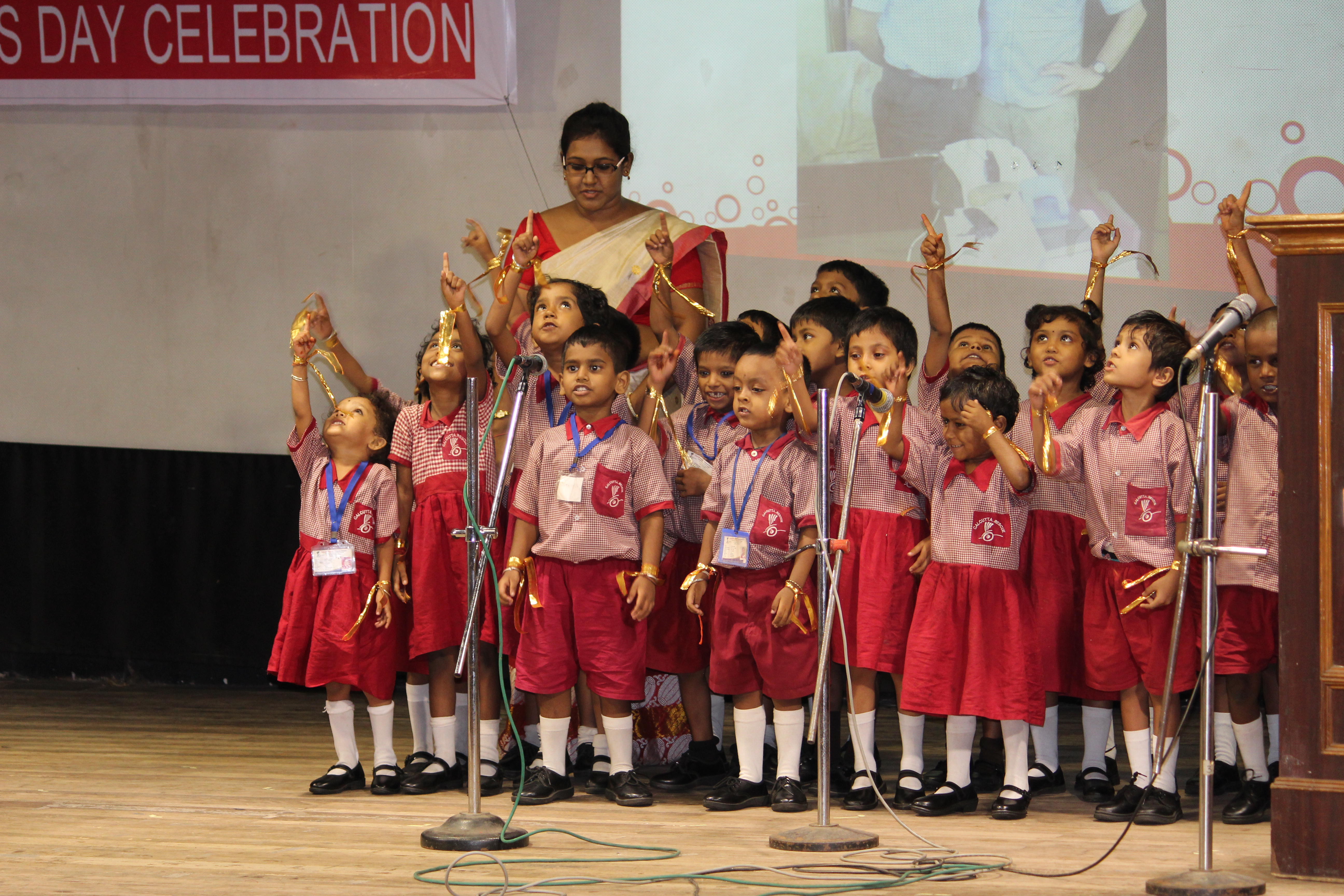 Die Schulkinder von Calcutta Rescue singen mit der Unterstützung ihrer Lehrerin am ersten Gründertag.