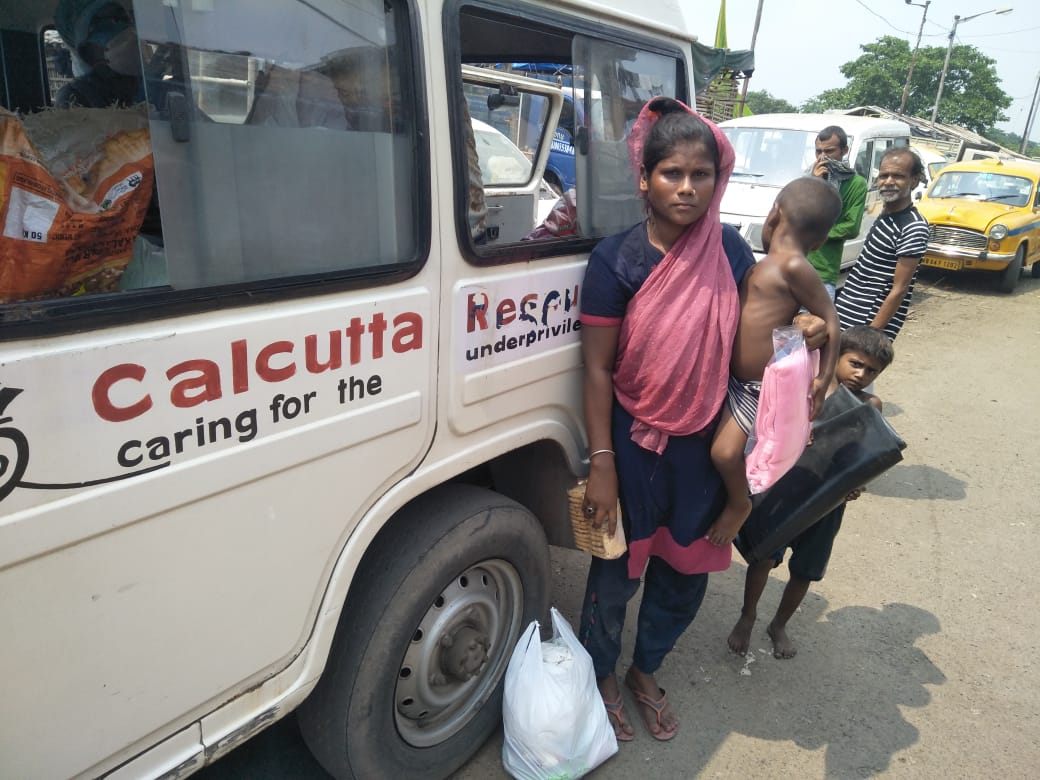 Calcutta Rescue verteilt Planen und Essen an eine Frau und ihre beiden Kinder. 